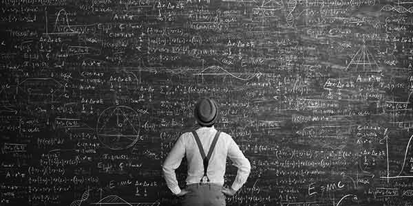 Man in front of a giant chalkboard with equations filling it.